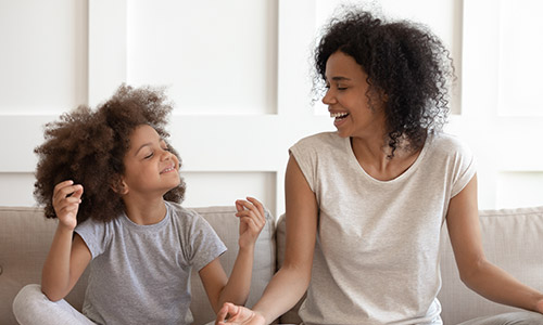 Woman and a girl sitting on a couch meditating.