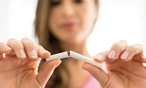 Woman breaking a cigarette in half.